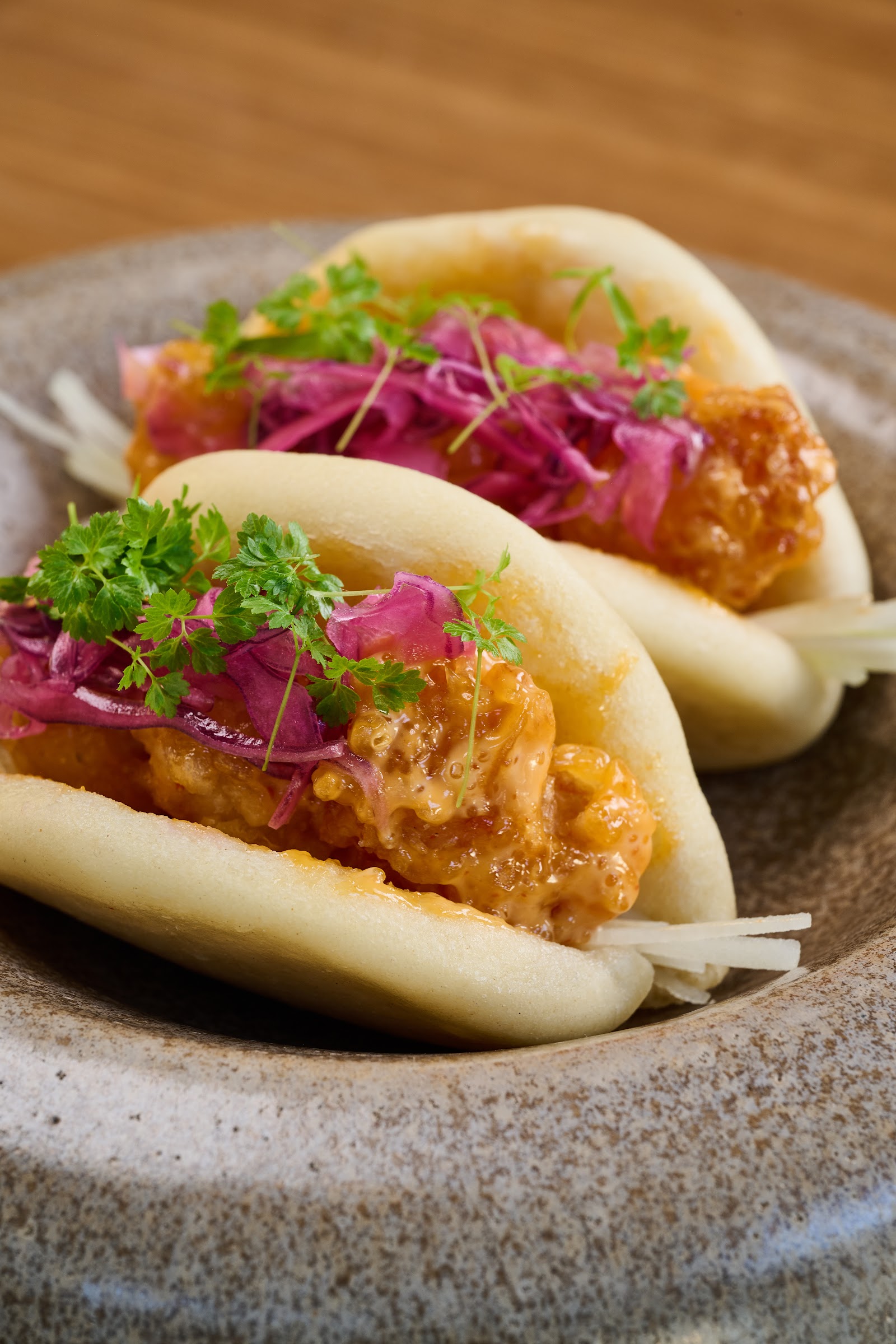 Baos com camarão crocante (rock shrimp) ao molho cremoso, repolho roxo em conserva e ervas frescas, em tigela de cerâmica artesanal